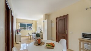 A dining area with a round table, white chairs, a coffee pot, and a fruit basket. - Casa Miramar 2 – Comfort and Unbeatable Location in the Heart of San Sebastián (San Sebastian de La Gomera)