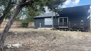 A residential property with a fenced yard, a wooden deck, and a house with a dark exterior.