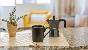 Een keukentrap met een koffiezetapparaat, een mok en een bloempot.