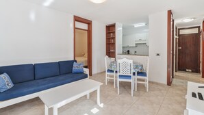 Un soggiorno con un divano blu, un tavolino da caffè bianco e un'area pranzo con tavolo e sedie.