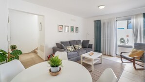 En stue med en grå sofa, et hvidt sofabord og et spiseområde med et hvidt bord.