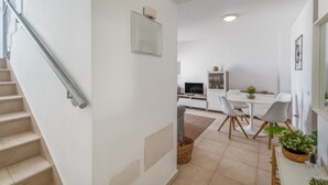 Et moderne interiør med en trappe, et spiseområde med et bord og stole, og et køkken i baggrunden.