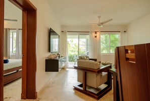 A spacious room with a bed, a sofa, a dining table, and a ceiling fan. - Private Beach | Terrace and Pool • Fast WiFi (Punta Cana)