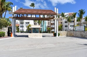 A hotel entrance with a covered walkway, a stone wall, and a sign for 'Playa Turquesa'. - Private Beach | Terrace and Pool • Fast WiFi (Punta Cana)