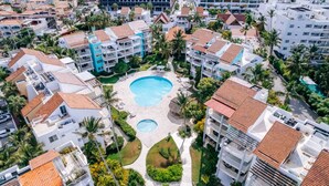 An aerial view of a resort with multiple buildings, a central swimming pool, and surrounding greenery. - Private Beach | Terrace and Pool • Fast WiFi (Punta Cana)