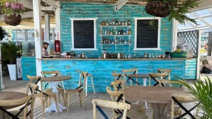 An outdoor bar area with wooden tables and chairs, a turquoise bar counter, and a menu board. - Private Beach | Terrace and Pool • Fast WiFi (Punta Cana)