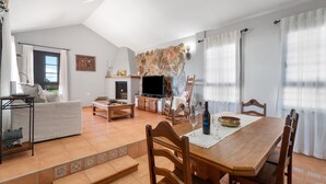 Ein geräumiger Wohnbereich mit einer Couch, einem Fernseher, einem Esstisch und Stühlen.
