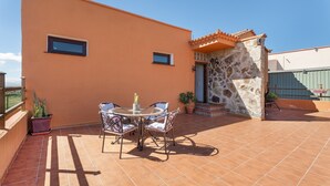 Eine Terrasse mit rundem Tisch und Stühlen, einem Blumentopf und einer Steinmauer.
