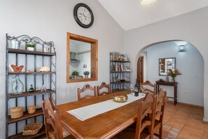 A dining area with a wooden table, chairs, and shelves with decorative items.