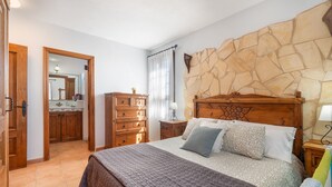 Ein Schlafzimmer mit einem großen Bett, einem Holzkopfende, einem Schminktisch, einem Spiegel und einer Steinwand.