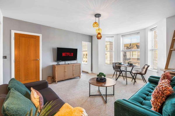 Spacious living area with two large sofas and a bay window framing a small but lovely sea-view