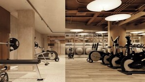 Een sportschool met trainingsapparatuur, waaronder loopbanden, hometrainers en een bank.