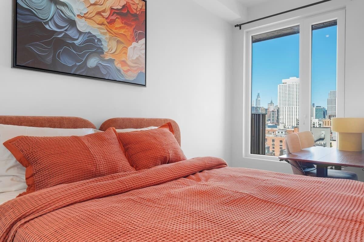 Une chambre d’hôtel avec un grand lit, une vue sur la ville et un tableau au mur.