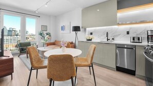 Een moderne keuken met een vaatwasser, een fornuis en een magnetron. Er is een eethoek met een ronde tafel en stoelen.