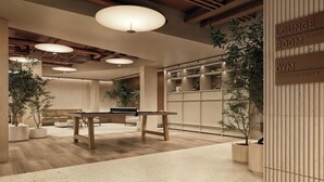 Een moderne loungeruimte met een pooltafel, zitplaatsen en een bord dat de aanwezigheid van een fitnessruimte aangeeft.