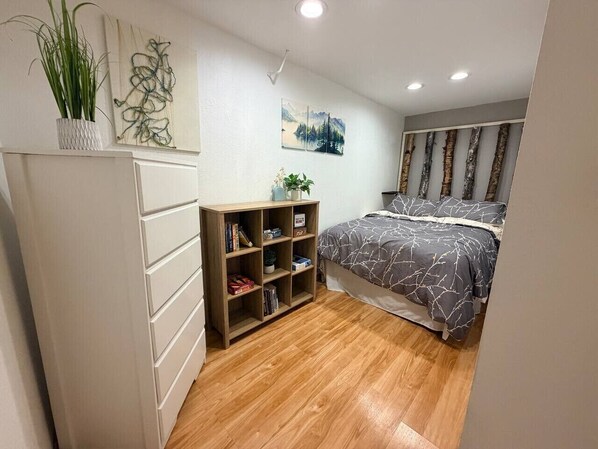 A bedroom with a bed, a bookshelf, and a wall-mounted painting.