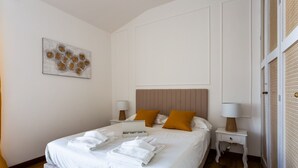A neatly made bed with white linens and two pillows, a bedside table with a lamp, and a wall-mounted artwork. - Saint Peter's Luxury Terrace Suites (Roma)