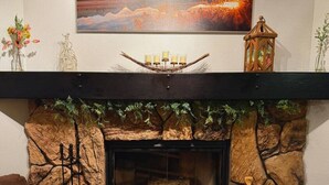 A cozy living room with a stone fireplace, a mounted painting, and a decorative lantern. - Nordic Retreat with private Finnish Sauna (Anchorage)