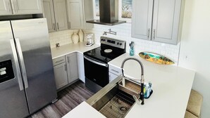A modern kitchen with stainless steel appliances, white cabinetry, and a black stove. - Jensen Jewel:  
Clean, new, one bedroom in the beautiful Ocean View community (Jensen Beach)