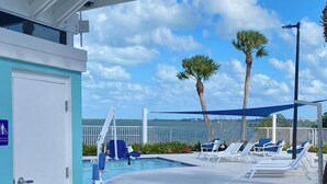 A poolside area with lounge chairs, a lifeguard stand, and a view of the ocean. - Jensen Jewel:  
Clean, new, one bedroom in the beautiful Ocean View community (Jensen Beach)