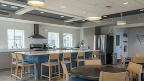 A modern kitchen with a central island, bar stools, and a round dining table with chairs. - Jensen Jewel:  
Clean, new, one bedroom in the beautiful Ocean View community (Jensen Beach)