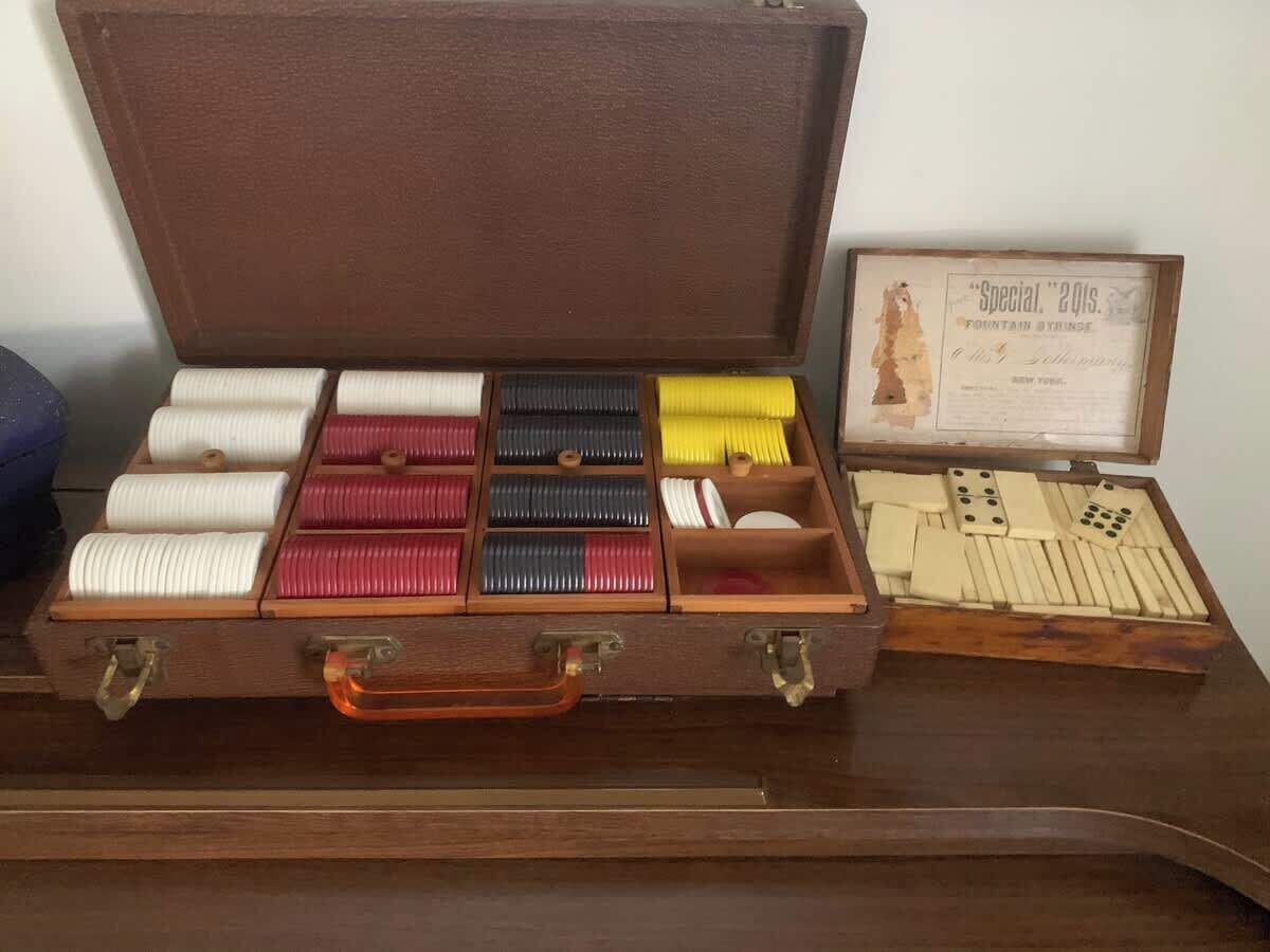 A wooden case with compartments containing various colored spools of thread and a set of dominoes.