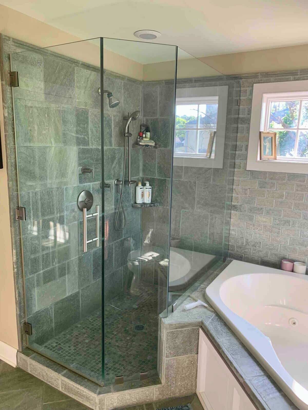 A modern bathroom with a glass-enclosed shower, a freestanding bathtub, and a stone-tiled shower area.