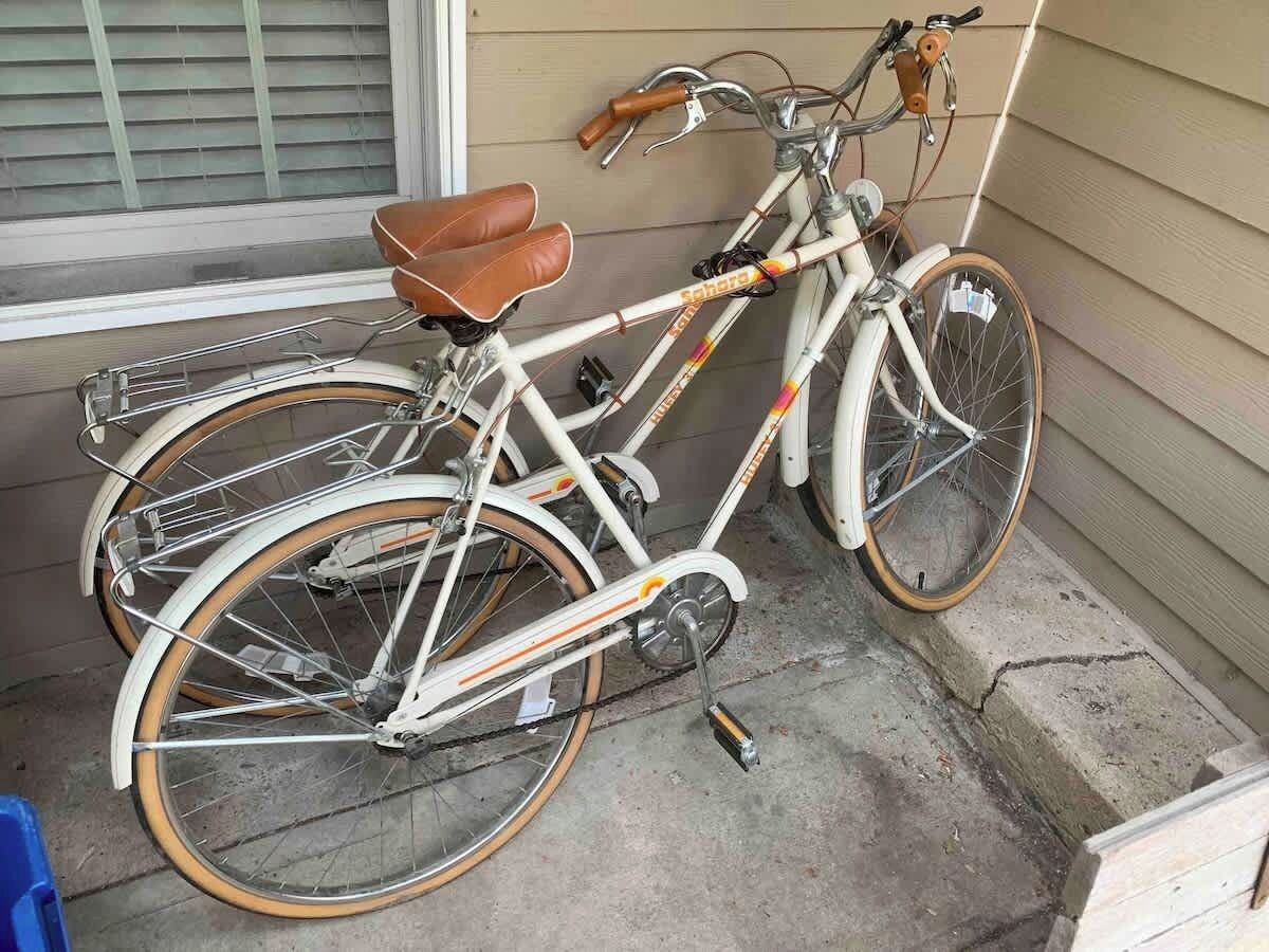 Una bicicleta blanca con detalles naranja estacionada frente a una casa.