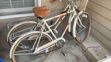 Una bicicleta blanca con detalles naranja estacionada frente a una casa.
