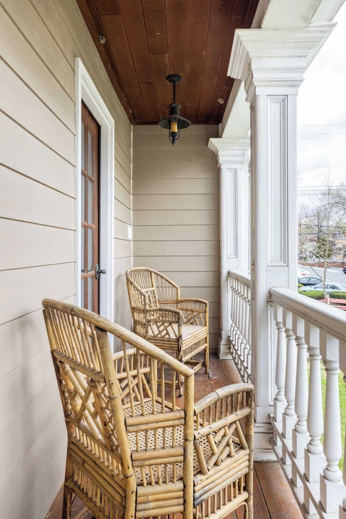 A wooden porch with two wicker chairs and a ceiling light fixture.