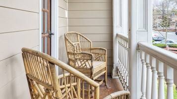 A wooden porch with two wicker chairs and a ceiling light fixture.