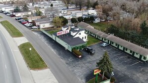 A motel with a large parking lot and a building with a green roof. - By The Way Motel Lake Bluff (Lake Bluff)