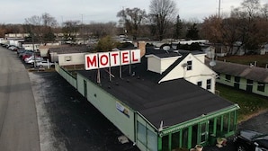 A motel with a prominent 'MOTEL' sign, a parking lot, and several buildings with satellite dishes. - By The Way Motel Lake Bluff (Lake Bluff)
