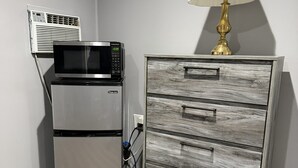 A kitchenette with a microwave, refrigerator, and a wooden cabinet with drawers. - By The Way Motel Lake Bluff (Lake Bluff)
