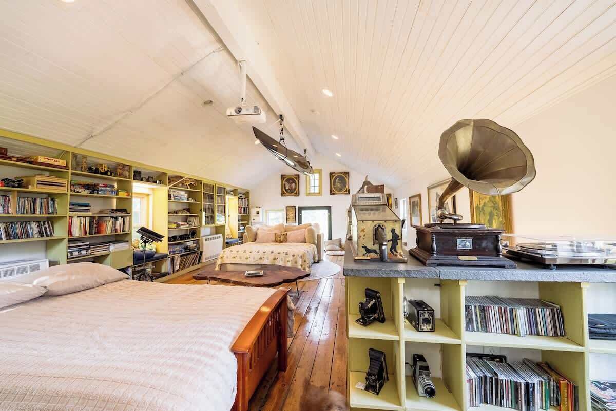 A cozy room with a bed, bookshelves, a desk, and a vintage gramophone.