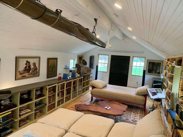 Una habitación acogedora con una cama, una mesa de madera, una estantería y un ventanal grande.