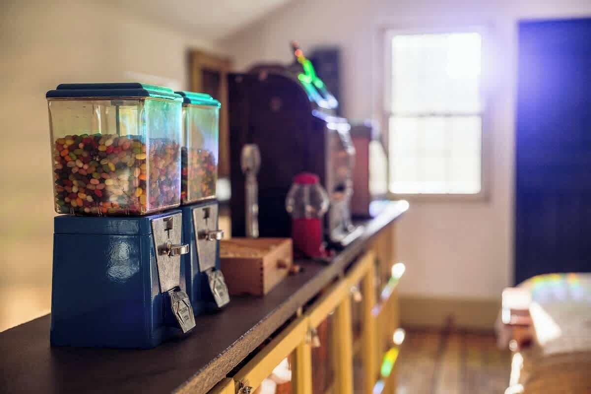 A row of vintage candy dispensers on a wooden counter with a window in the background.