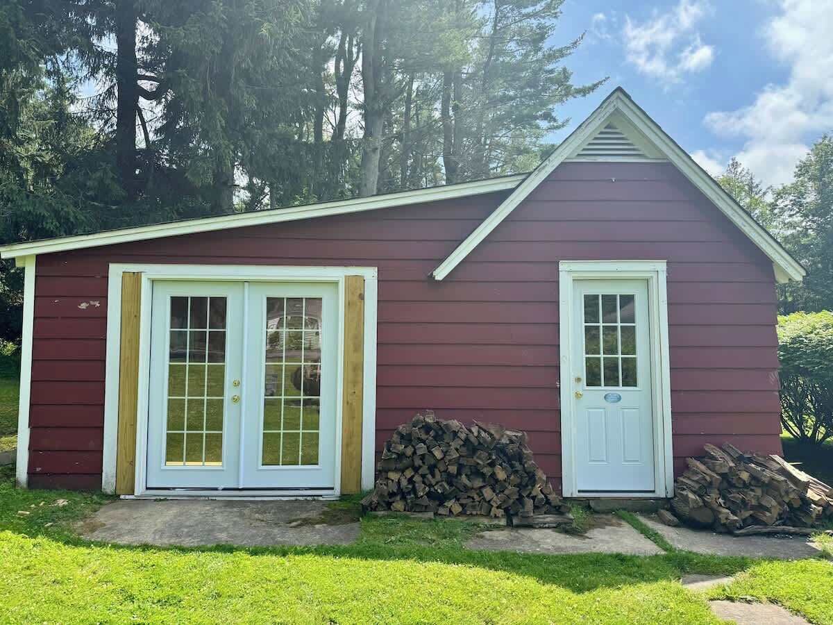 Il s’agit d’un petit bâtiment d’un seul étage, à l’extérieur rouge et aux bordures blanches. Il possède deux portes d’entrée, l’une avec des panneaux de verre et l’autre avec un panneau plein. Une pile de bois de chauffage se trouve à côté de la porte de droite.