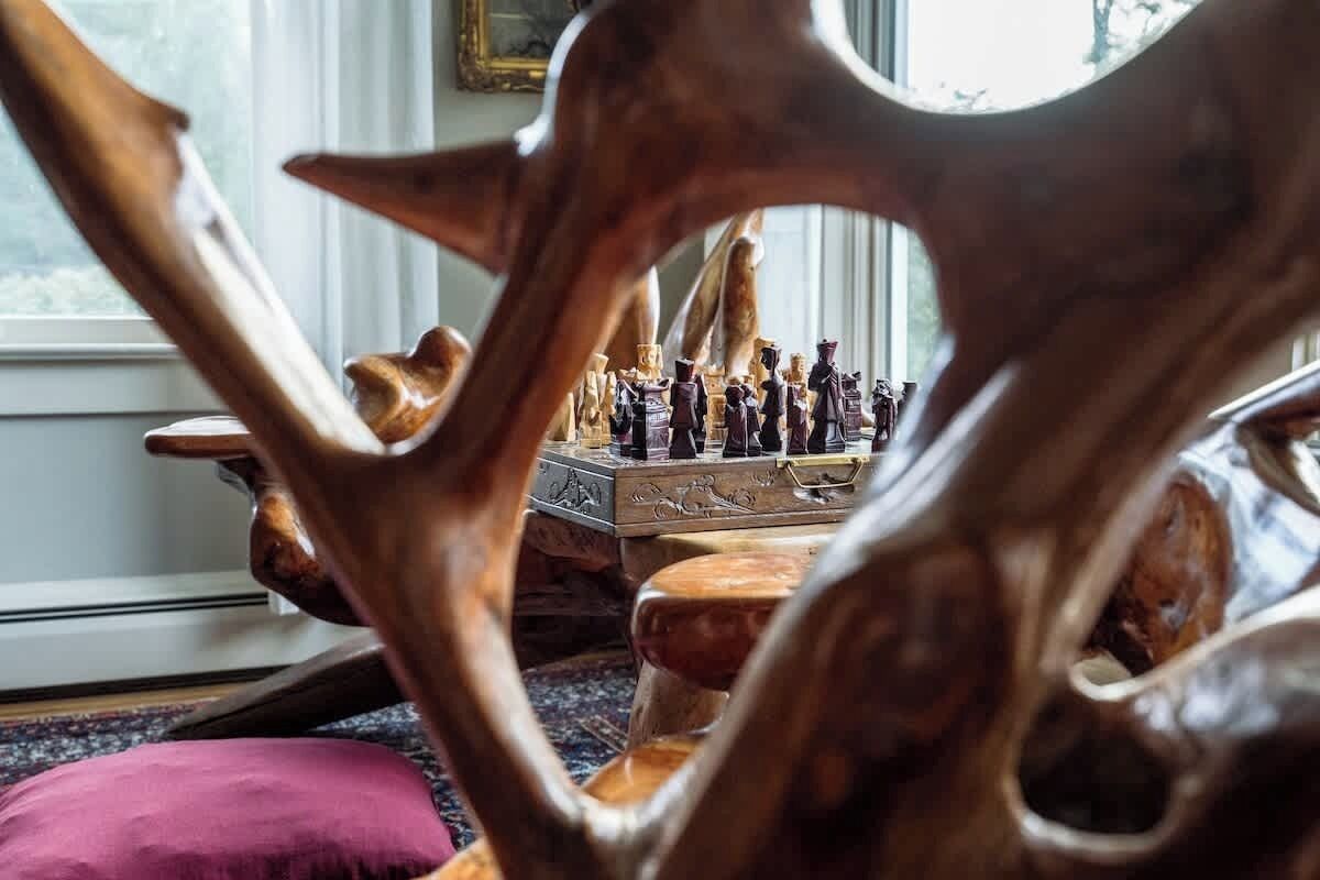 A chessboard set on a wooden table with a window in the background.