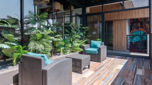 Een moderne buitenruimte met rieten meubilair en een houten vloer.