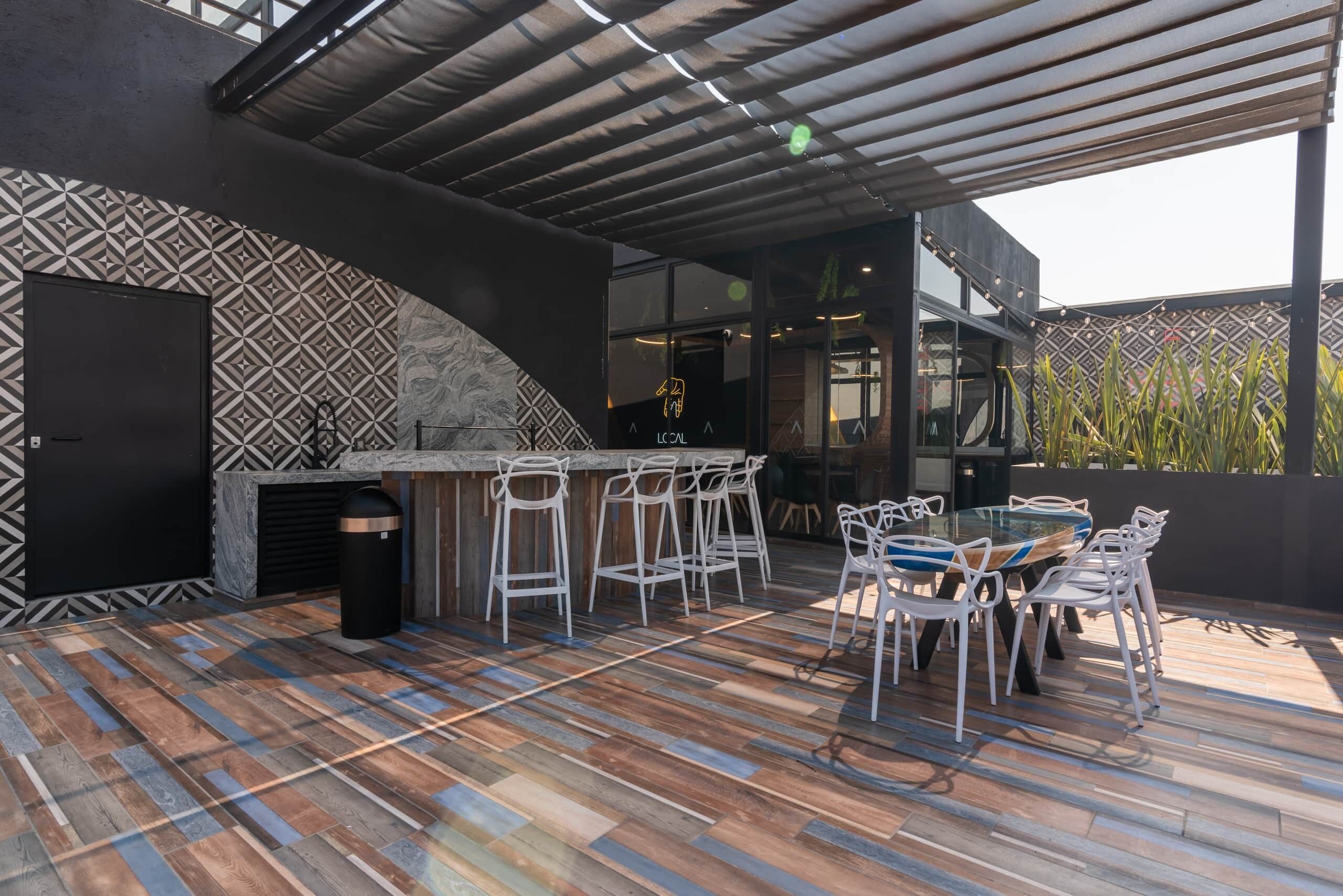 An outdoor patio with a bar area, seating, and a patterned wall.