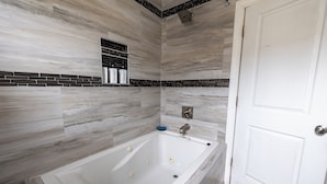 Un baño moderno con una bañera grande, una ducha y una puerta blanca.