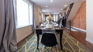Un comedor con una mesa dispuesta para cuatro personas, una escalera y una pared de ladrillo.