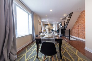 A dining area with a table set for four, a staircase, and a brick wall.