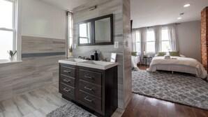 Un baño moderno con tocador doble, un espejo grande y zona de ducha.