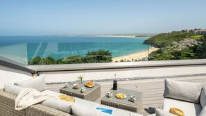 A balcony with wicker furniture, a glass balustrade, and a view of a beach and ocean. - 1 Moonrakers - Three Bedroom House, Sleeps 6 (Carbis Bay)