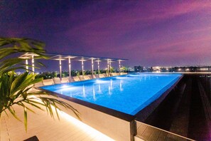 Une piscine à débordement offrant une vue sur les gratte-ciel de la ville au crépuscule.