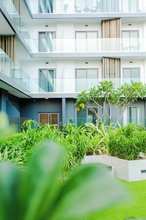 Un bâtiment moderne à plusieurs étages, doté de grandes fenêtres et d’une cour intérieure agrémentée de verdure.