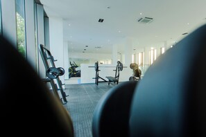 Une salle de sport équipée de matériel d’exercice, dotée de grandes fenêtres et d’un aménagement intérieur moderne.