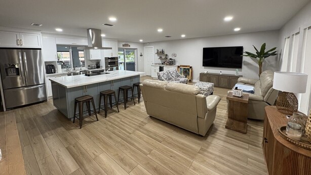 A modern kitchen with a central island, a dining area with a sofa, and a living room with a TV. - Casa Del Mar Waterfront Home On Dawon Canal!
Boat Lift and Hot Tub (Saint James City)